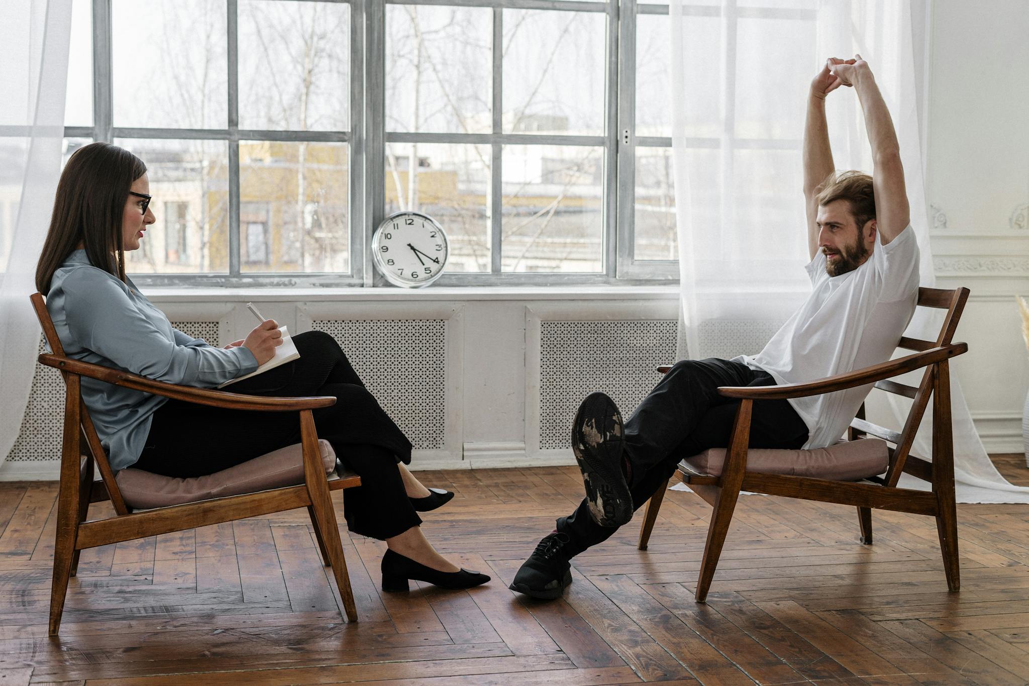 Man in White Dress Shirt and Black Pants Sitting on Brown Wooden Chair